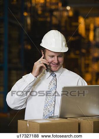 Stock Photo - Businessman talking on cell phone in warehouse. Fotosearch