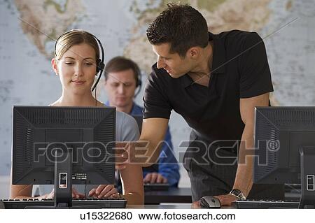 Stock Image - Businessman training call center employee. Fotosearch