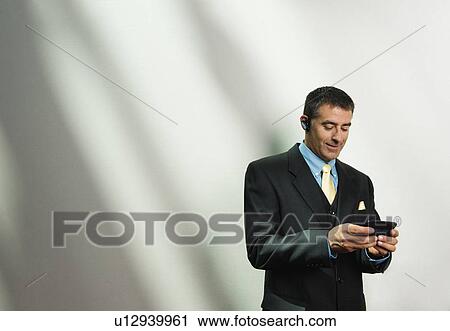 Businessman using cell phone and hands-free device View Large Photo Image Stock Image - Businessman using cell phone and hands-free device. Fotosearch