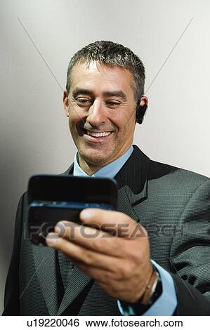 Businessman using cell phone and hands-free device View Large Photo Image Stock Photograph - Businessman using cell phone and hands-free device. Fotosearch