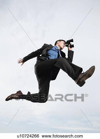 Stock Photograph - Businessman with binoculars jumping in mid-air. Fotosearch