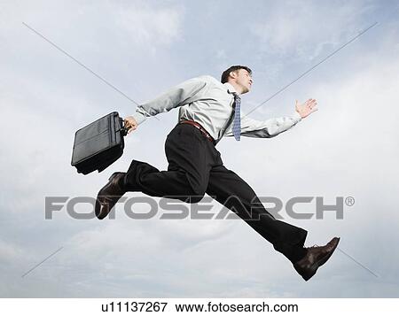 Businessman with briefcase jumping in mid-air View Large Photo Image Stock Photo - Businessman with briefcase jumping in mid-air. Fotosearch