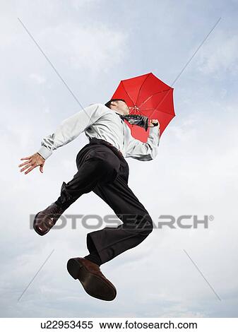 Businessman with umbrella jumping in mid-air View Large Photo Image Stock Photography - Businessman with umbrella jumping in mid-air. Fotosearch