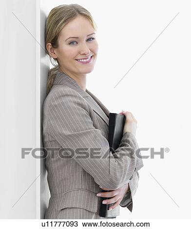 Stock Image - Businesswoman leaning against wall. Fotosearch