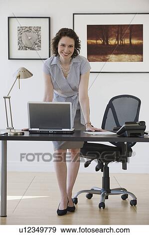 Stock Photo - Businesswoman leaning on desk. Fotosearch