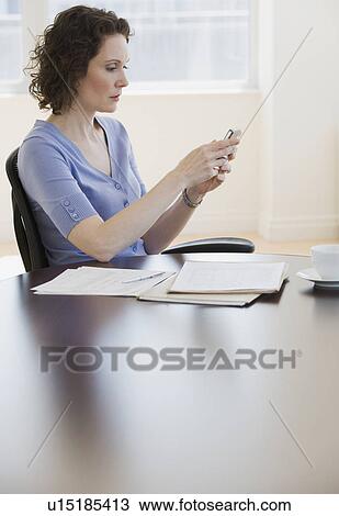 Stock Image - Businesswoman looking at electronic organizer. Fotosearch