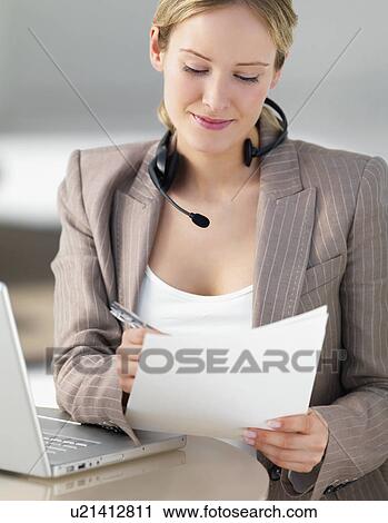 Stock Image - Businesswoman reviewing paperwork. Fotosearch