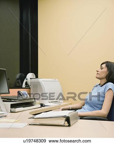 Stock Photo - Businesswoman sitting at desk. Fotosearch