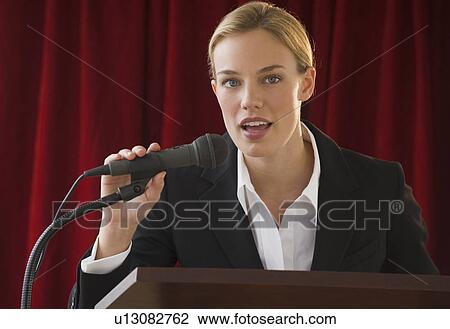 Stock Image - Businesswoman speaking into microphone. Fotosearch