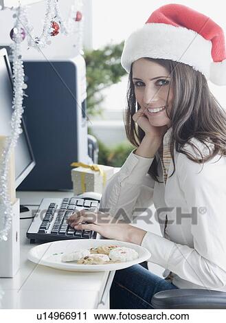 Stock Image - Businesswoman wearing Santa Claus hat. Fotosearch