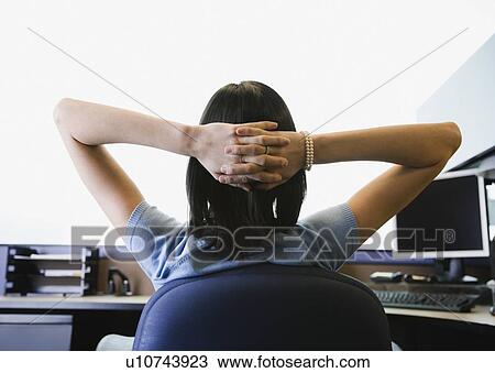 Stock Image - Businesswoman with hands behind head. Fotosearch