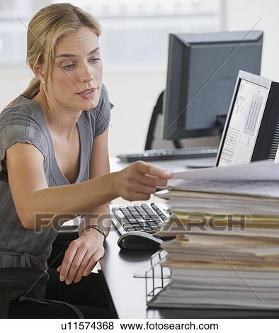 Businesswoman with stack of paperwork on desk View Large Photo Image Stock Photo - Businesswoman with stack of paperwork on desk. Fotosearch