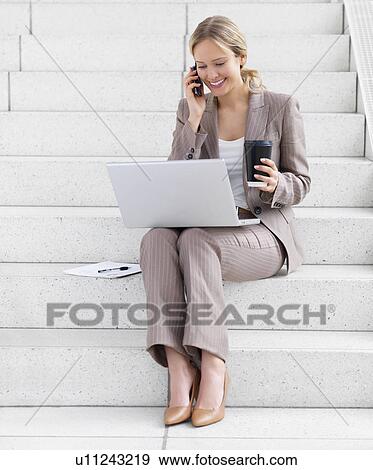 Businesswoman working on laptop and talking on cell phone View Large Photo Image Stock Photo - Businesswoman working on laptop and talking on cell phone. Fotosearch