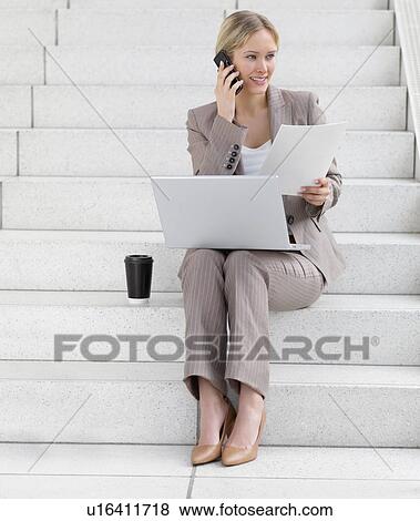Businesswoman working on laptop and talking on cell phone View Large Photo Image Stock Photo - Businesswoman working on laptop and talking on cell phone. Fotosearch
