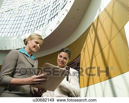 Businesswomen discussing file in office View Large Photo Image Stock Photo - Businesswomen discussing file in office. Fotosearch