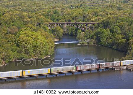 Stock Image - Cargo train on rail over river, New York, United States. Fotosearch