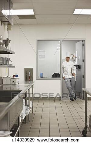 Stock Photo - Chef standing in doorway of kitchen office. Fotosearch