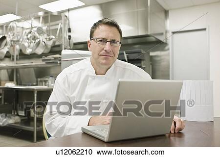Chef working on laptop in kitchen View Large Photo Image Stock Image - Chef working on laptop in kitchen. Fotosearch