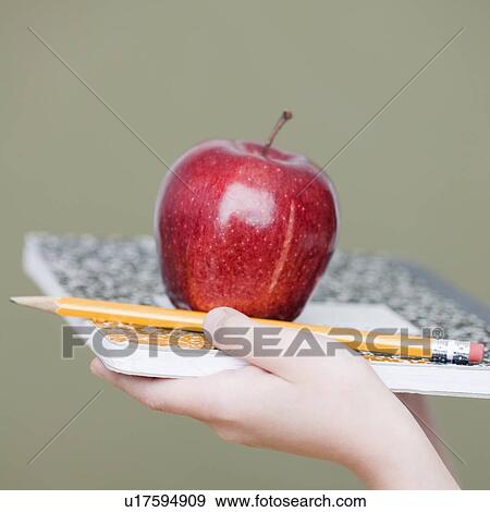 Stock Photo - Child holding apple and pencil on notebook. Fotosearch