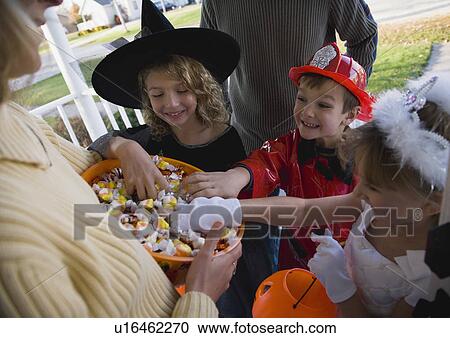 Children in Halloween costumes reaching into bowl of candy View Large Photo Image Stock Image - Children in Halloween costumes reaching into bowl of candy. Fotosearch