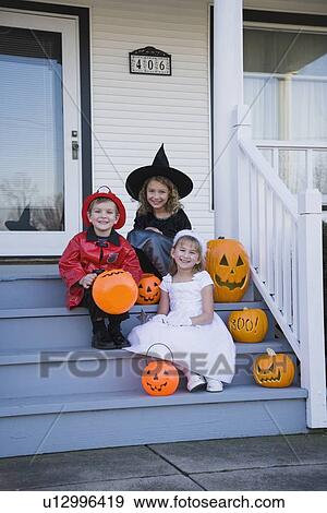 Stock Photo - Children in Halloween costumes sitting on porch. Fotosearch
