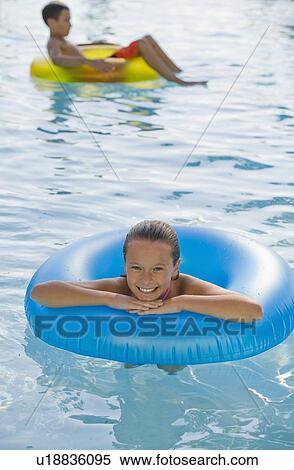 Stock Photography - Children playing with inflatable tubes in swimming pool. Fotosearch