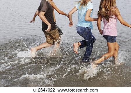 Stock Image - Children running in ocean. Fotosearch