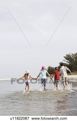Stock Photo - Children running in ocean. Fotosearch
