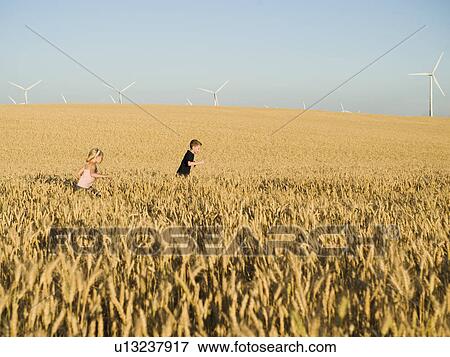Children running through tall wheat field on wind farm View Large Photo Image Stock Photo - Children running through tall wheat field on wind farm. Fotosearch
