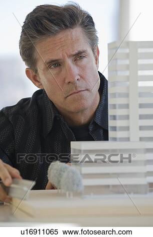 Stock Photography - Close up of architect examining building model. Fotosearch