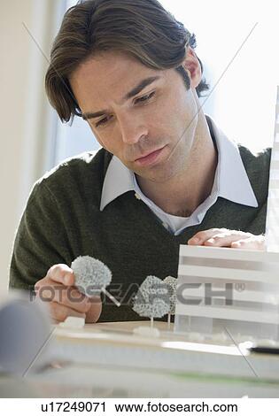 Stock Image - Close up of architect working on building model. Fotosearch