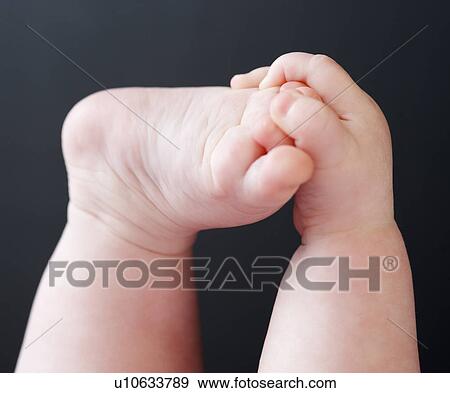 Stock Photo - Close up of baby grabbing foot. Fotosearch