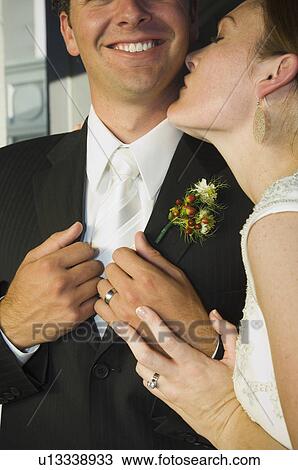 Stock Image - Close up of bride kissing groom. Fotosearch