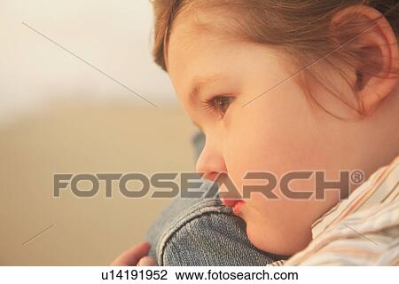 Stock Image - Close up of child resting on parent’s shoulder. Fotosearch