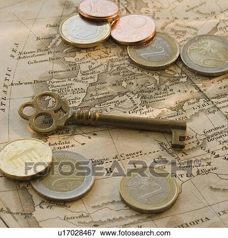 Stock Photo - Close up of euro coins, map and antique key. Fotosearch
