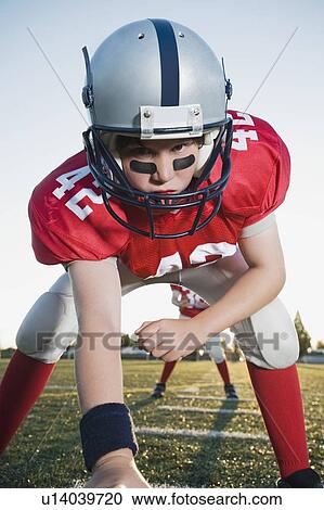 Stock Image - Close up of football center preparing to snap football. Fotosearch