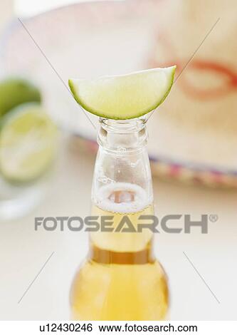 Close up of lime balancing on beer bottle View Large Photo Image Stock Photograph - Close up of lime balancing on beer bottle. Fotosearch