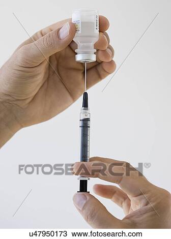 Stock Image - Close up of man filling syringe. Fotosearch