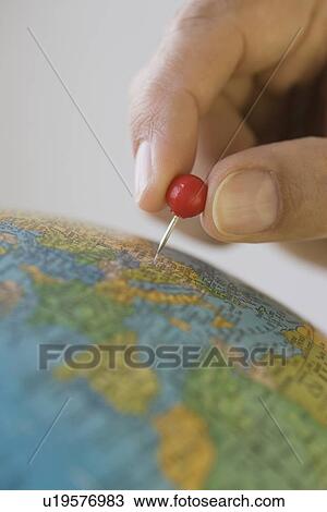 Stock Image - Close up of pin marking place on globe. Fotosearch