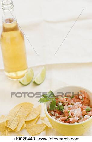 Stock Image - Close up of salsa, tortilla chips and beer. Fotosearch