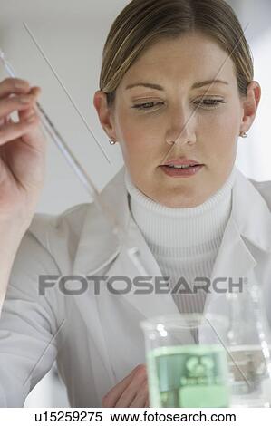 Stock Photography - Close up of scientist extracting liquid from beaker. Fotosearch