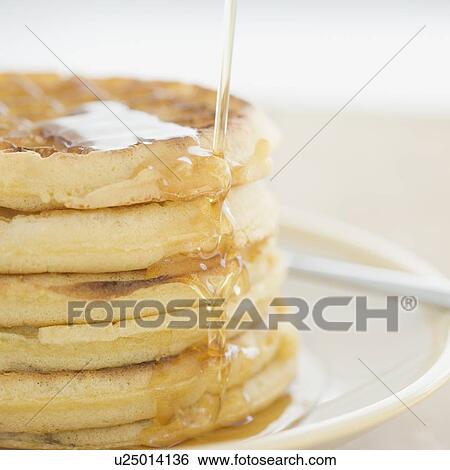 Stock Photograph - Close up of syrup pouring on waffles. Fotosearch