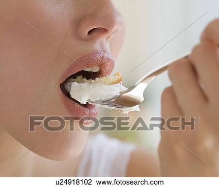 Stock Image - Close up of woman eating cake. Fotosearch