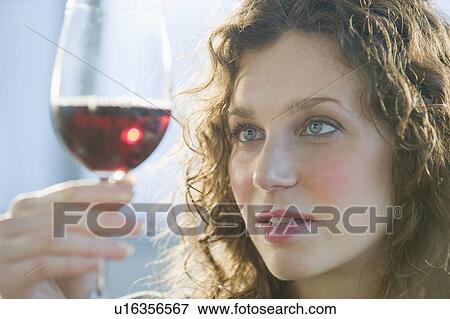 Stock Photo - Close up of woman examining coloring of red wine. Fotosearch
