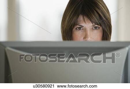 Stock Image - Close up of woman looking at computer monitor. Fotosearch