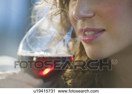 Stock Image - Close up of woman smelling red wine. Fotosearch