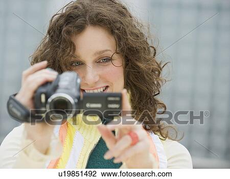Stock Image - Close up of woman using video camera. Fotosearch
