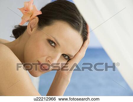 Stock Photograph - Close up of woman with flower in hair. Fotosearch