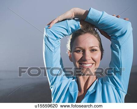 Stock Image - Close up of woman with hands overhead on foggy beach. Fotosearch