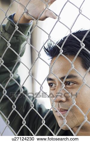 Close up of young man leaning against chain-link fence View Large Photo Image Stock Image - Close up of young man leaning against chain-link fence. Fotosearch